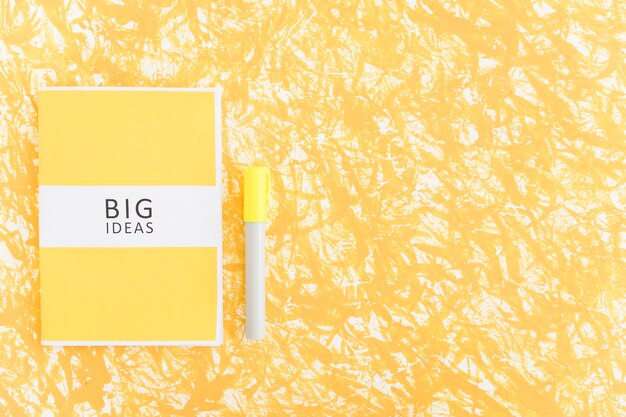 Diário de grandes ideias e marcador em fundo amarelo texturizado
