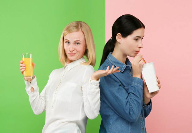 Dieta. Conceito de dieta. Comida saudável. Jovens mulheres bonitas que escolhem entre o suco de laranja e a bebida doce não carbonatada