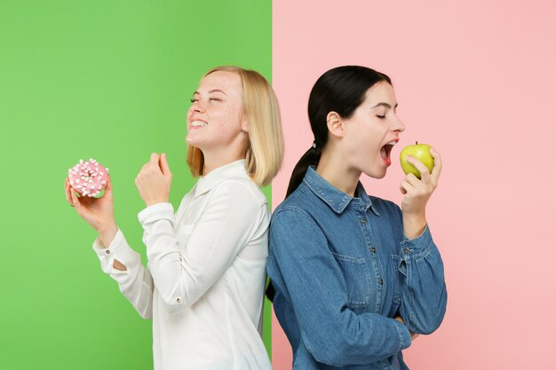 Dieta. Conceito de dieta. Comida saudável. Moças lindas escolhendo entre frutas e bolo sem-fé