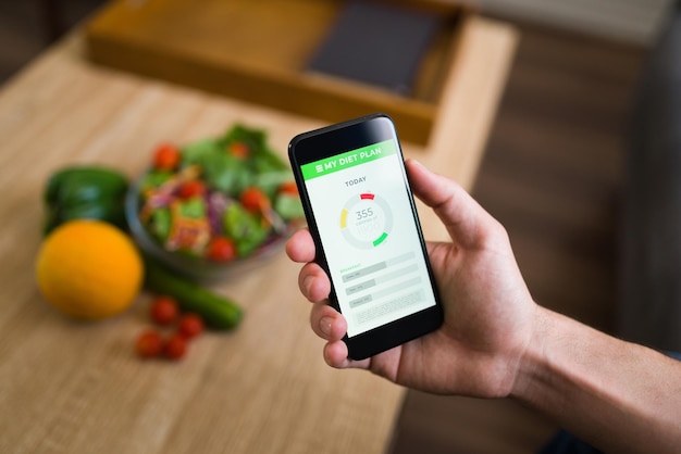 Foto grátis dieta saudável. mãos masculinas segurando um smartphone e acompanhando as calorias de sua comida com um aplicativo de fitness