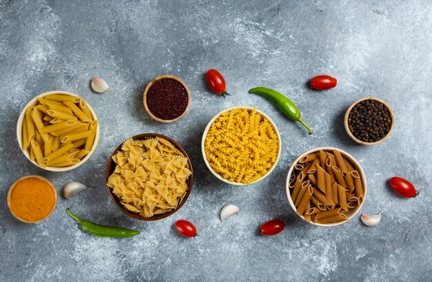 Diferentes tipos de macarrão e vegetais crus.