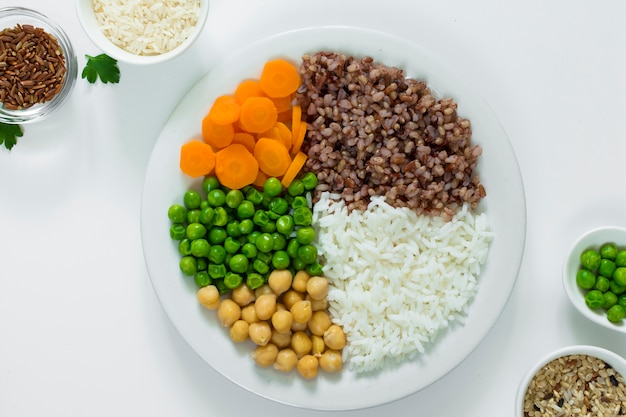 Diferentes tipos de mingau com legumes no prato com tigelas de arroz na mesa