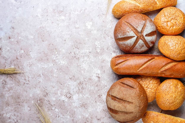Diferentes tipos de pão fresco como pano de fundo, vista superior Foto gratuita