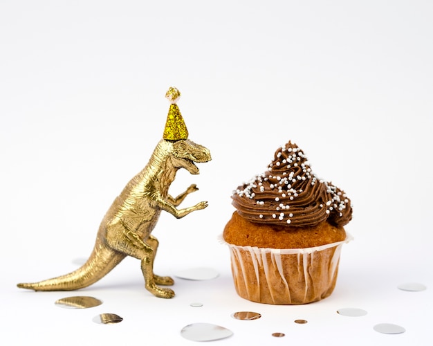 Dinossauro de brinquedo dourado e bolinho saboroso