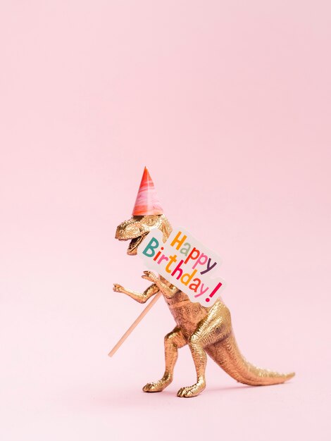 Dinossauro de brinquedo engraçado segurando placa de feliz aniversário