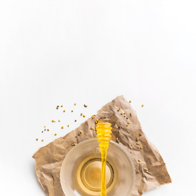 Dipper na tigela de mel com sementes de pólen de abelha sobre papel pardo