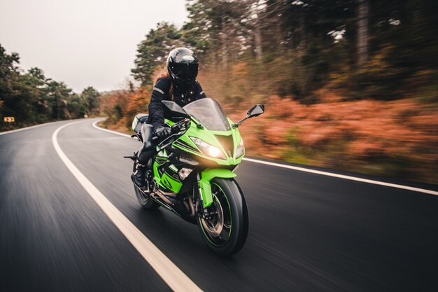 Dirigindo a motocicleta de cor verde neon na estrada.