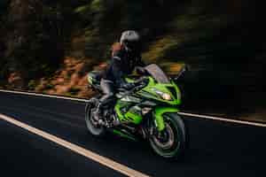 Foto grátis dirigindo moto verde na estrada.