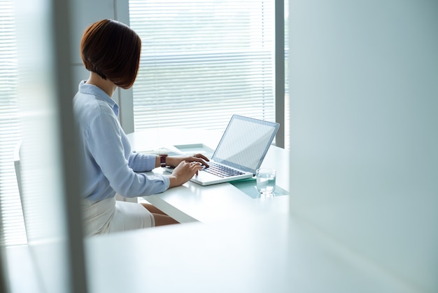 Disfarçado cam tiro de mulher de negócios, trabalhando no laptop no escritório