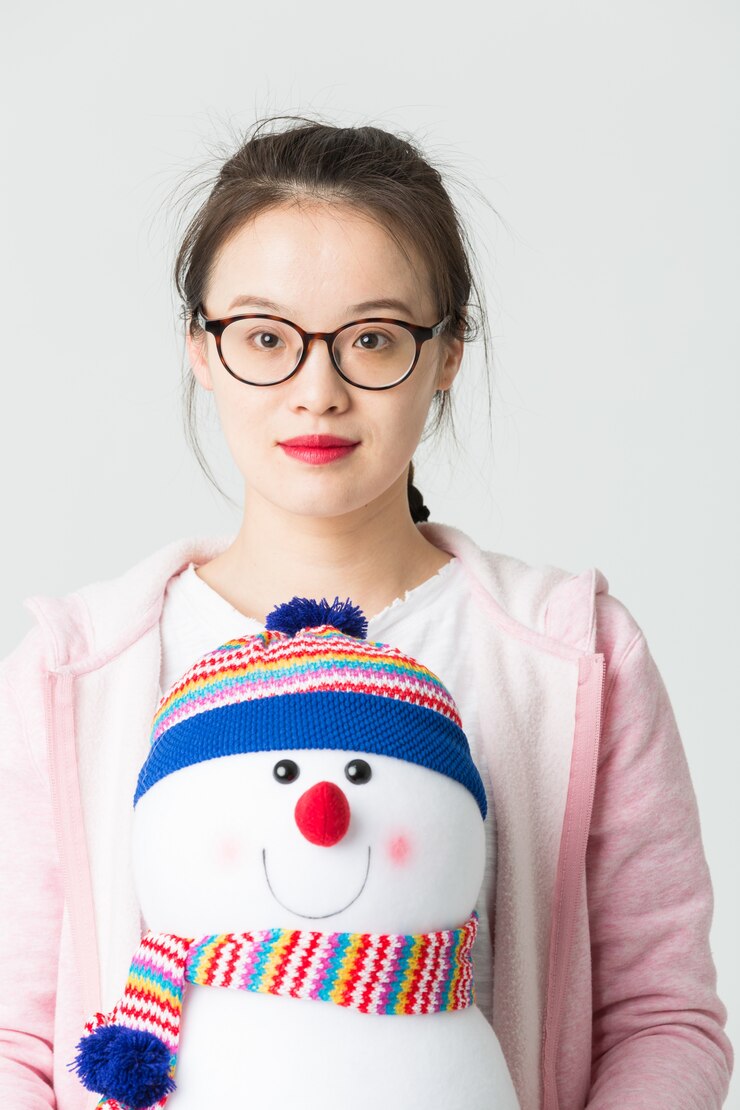 Foto grátis disparado no estúdio da jovem asiática segurando um boneco de neve de natal