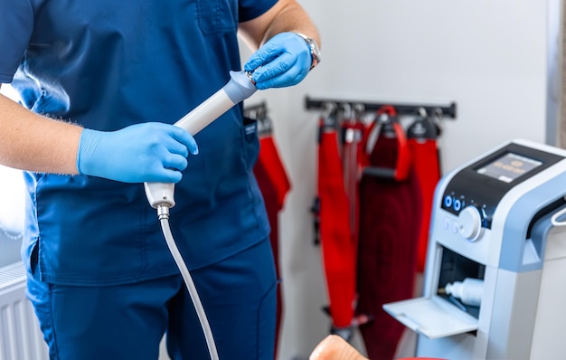 Foto grátis dispositivo de terapia por ondas de choque com mãos médicas em luvas de borracha