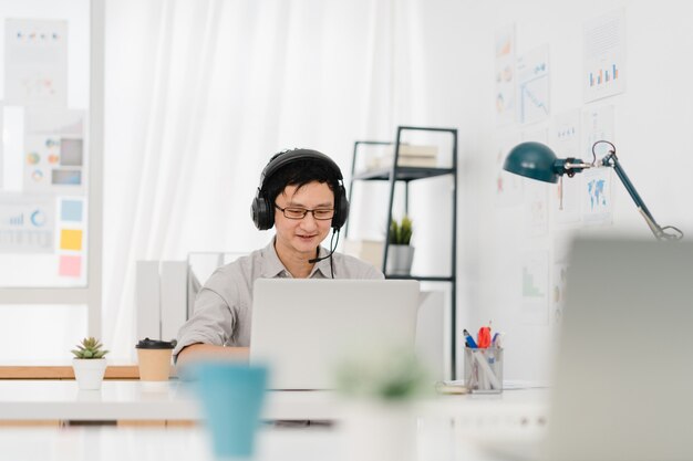 Distanciamento social do empresário Ásia na nova situação normal para prevenção de vírus usando laptop apresentação para colega sobre o plano de videochamada enquanto trabalha no escritório em casa. Estilo de vida após o vírus corona.