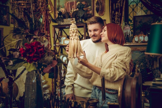 Diversão. Família sorridente, casal caucasiano, procurando a decoração da casa e presentes de Natal em uma loja doméstica. Coisas elegantes e retrô para saudações ou design. Renovação de interiores, comemorando o tempo.