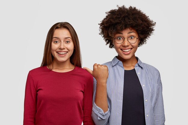 Diversas mulheres alegres parecem felizes, posam contra um espaço em branco, vestidas com roupas casuais