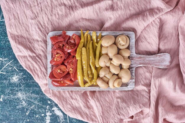 Diversos legumes em conserva na chapa branca com toalha de mesa.