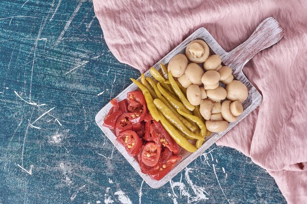 Diversos legumes em conserva na chapa branca com toalha de mesa.