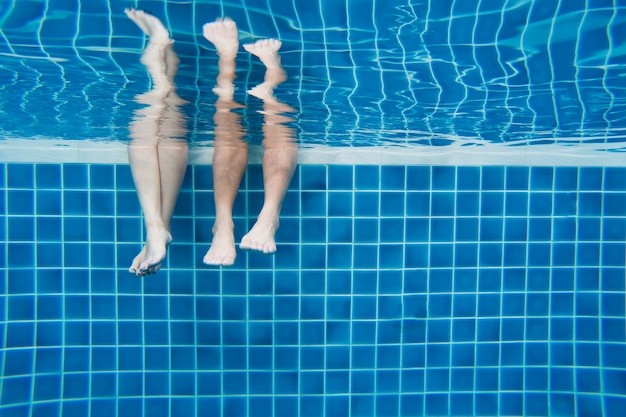 Divertidas pernas familiares subaquáticas em poo de natação