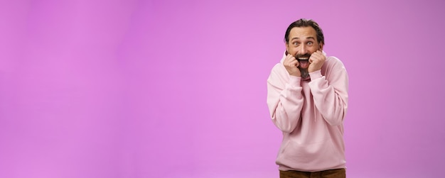 Divertido, emocionado, ofegante, bonito, feliz, homem adulto barbudo, com capuz rosa, inclinado, gritando de alegria.