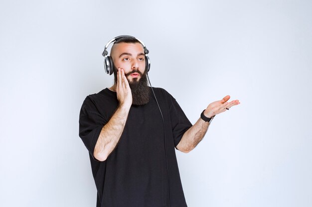 DJ com barba usando fones de ouvido, mostrando o lado direito e fica surpreso.