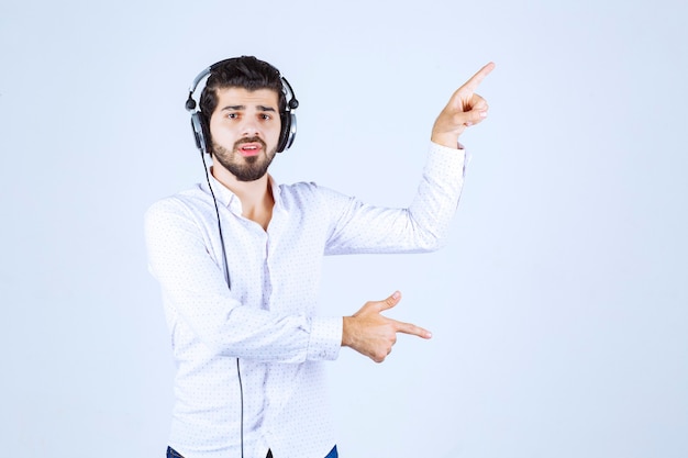 Dj com fones de ouvido dançando e apontando para alguém à direita