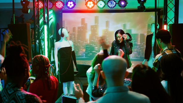 Foto grátis dj feminina se divertindo no palco da boate, criando uma atmosfera de boate na pista de dança. jovem misturando música eletrônica na festa discoteca para evento de celebração. tiro portátil.