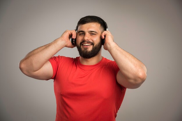 DJ masculino de camisa vermelha, usando fones de ouvido e ouvindo música.