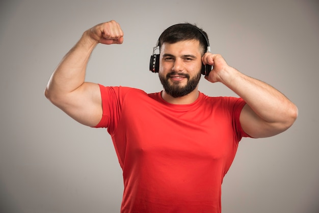 DJ masculino de camisa vermelha, usando fones de ouvido e se divertindo.