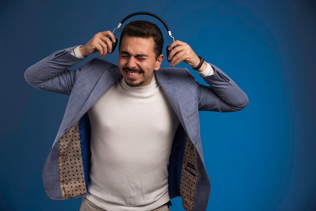 Foto grátis dj masculino em terno cinza usando fones de ouvido com volume alto.