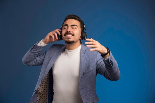 DJ masculino em terno cinza usando fones de ouvido e relaxantes.