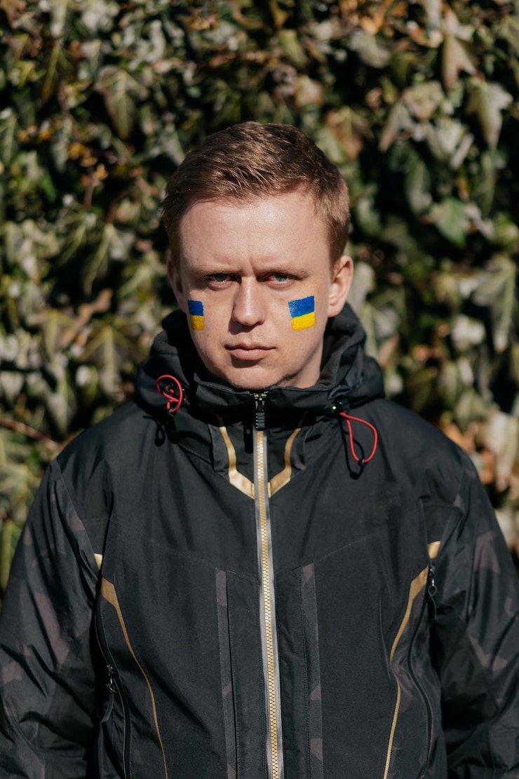Foto grátis do lado de fora, o retrato de um jovem com bandeira ucraniana no rosto está olhando para a câmera pare a guerra fique com a ucrânia apoie a ucrânia