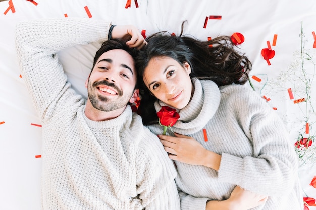 Foto grátis doce casal deitado no confetti