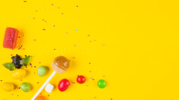 Foto grátis doces coloridos vívidos no fundo amarelo