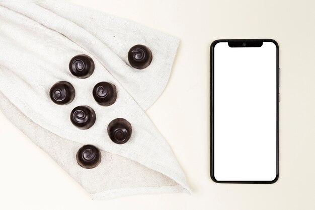 Doces de chocolate de vista superior com smartphone