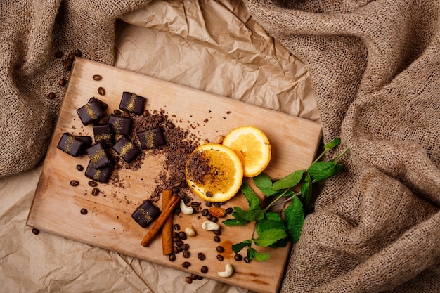 Foto grátis doces de chocolate laranja hortelã canela e nozes na mesa de madeira.