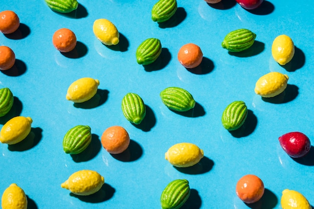 Doces de forma de fruta sobre o pano de fundo azul