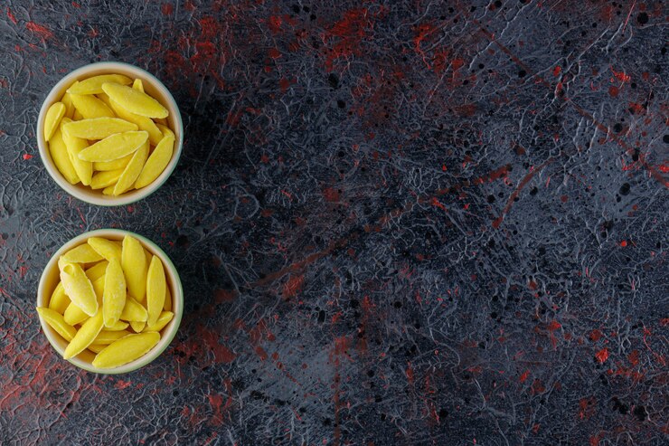 Foto grátis doces de mascar em forma de banana em uma mesa escura.