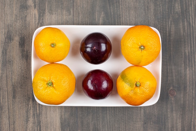 Doces tangerinas com ameixas em uma mesa de madeira. foto de alta qualidade