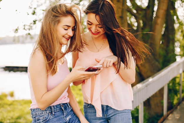 Foto grátis dois amigos bonitos e brilhantes em t-shirts cor de rosa e jeans azul andando no parque de verão