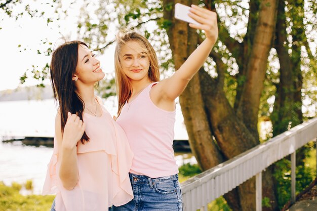 dois amigos bonitos e brilhantes em t-shirts cor de rosa e jeans azul andando no parque ensolarado