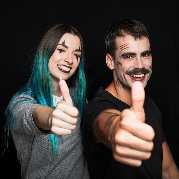 Dois amigos com maquiagem assustadora, colocando os polegares para cima