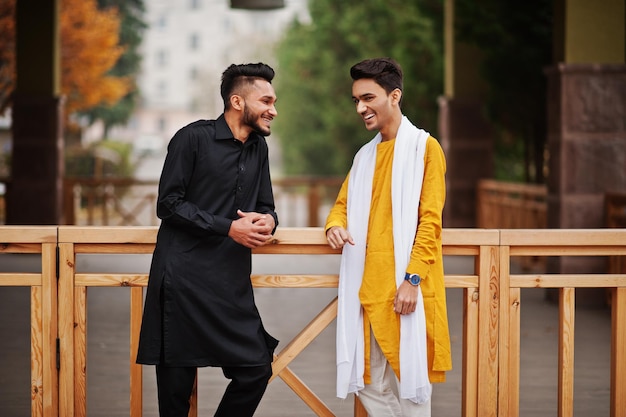 Dois amigos indianos elegantes em roupas tradicionais posaram para conversar e rir ao ar livre