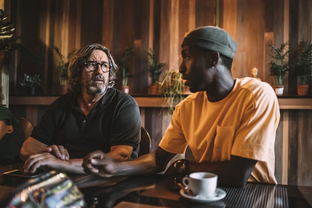 Dois amigos inter-raciais jantando e conversando em um restaurante