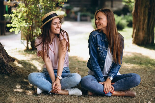 Dois amigos meninas, sentando, parque