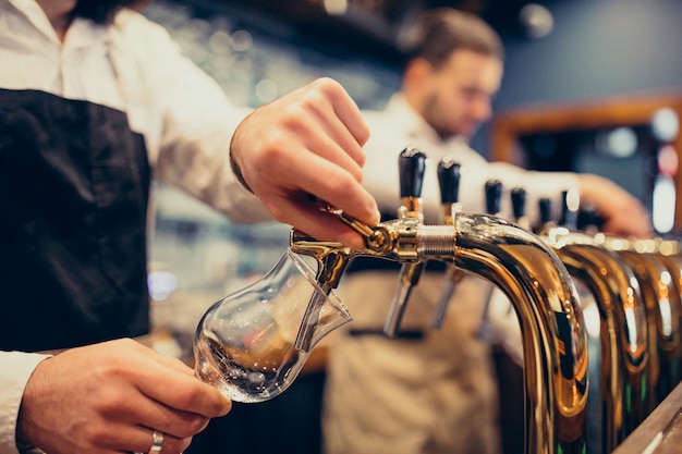 Dois barman bonitos que poring a cerveja no bar