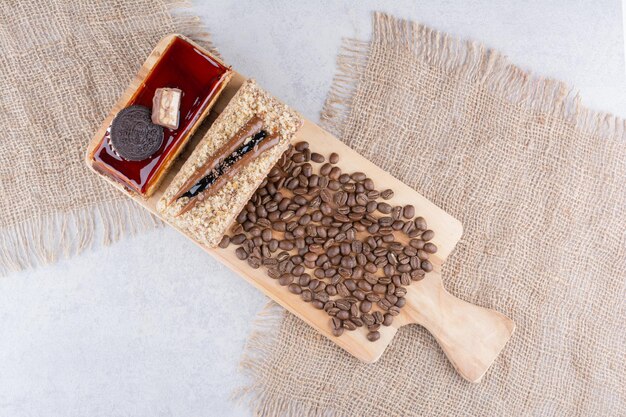 Dois bolos e grãos de café na placa de madeira. Foto de alta qualidade