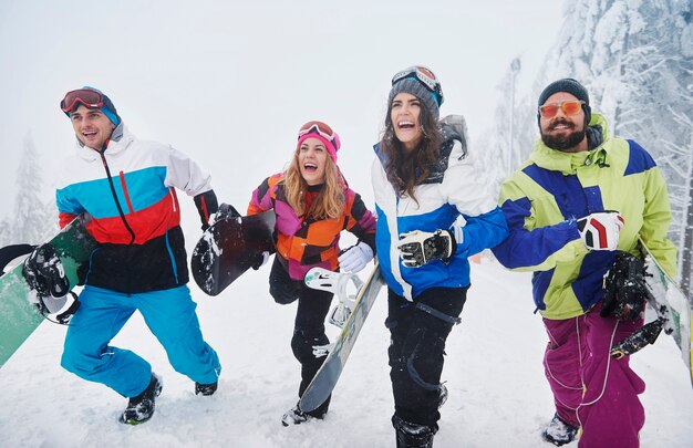 Dois casais se divertindo e praticando snowboard