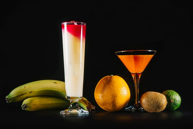 Dois cocktails e frutas exóticas em fundo preto