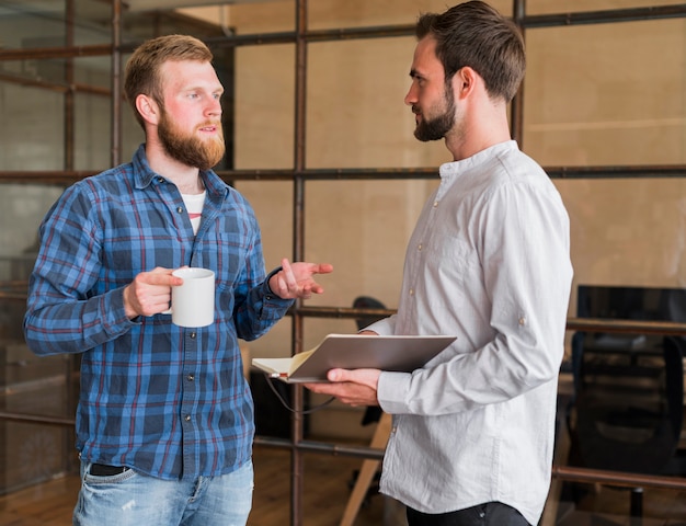 Dois colega masculina discutindo uns com os outros no local de trabalho