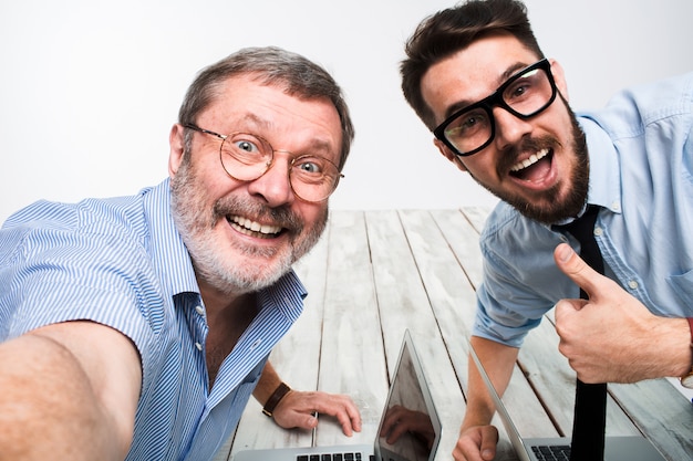 Dois colegas tirando a foto para eles auto sentado no escritório