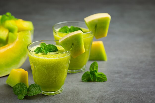 Dois copos de suco de melão colocados no chão escuro